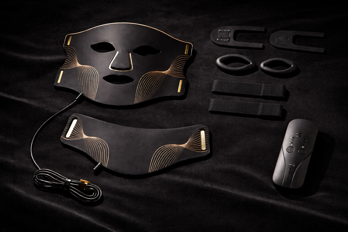 Aura Mask flat lay on black velvet showing face mask, neck attachment, handheld remote controller, charging cable, straps and accessories — Healing Circle
