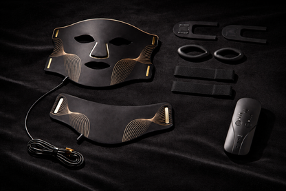 Aura Mask flat lay on black velvet showing face mask, neck attachment, handheld remote controller, charging cable, straps and accessories — Healing Circle